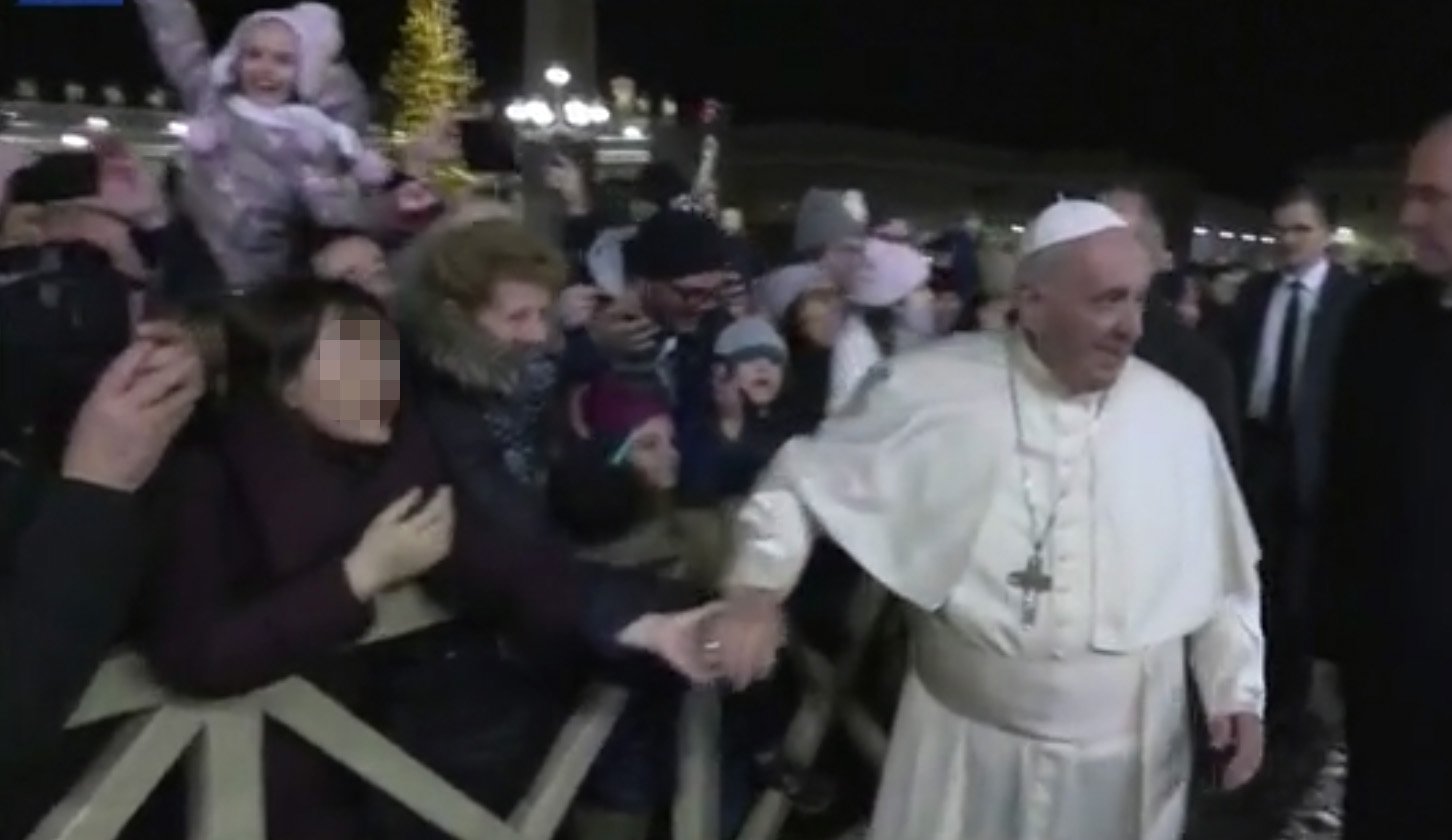 한 여성이 지난해 12월 31일 바티칸 성 베드로 광장에서 프란치스코 교황의 손을 잡아 당기고 있다. [사진 바티칸미디어 동영상 캡처]