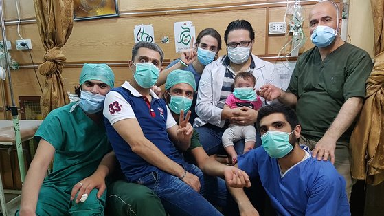 다큐멘터리 '사마에게'에서 시리아 반군 지역을 마지막까지 지켰던 의료진들. 맨가운데 아기 사마를 안은 사람이 함자. 동료들 중 일부는 내전 초기 정부군과 러시아군의 폭격에 당해 세상을 떠났다. [사진 엣나인필름]