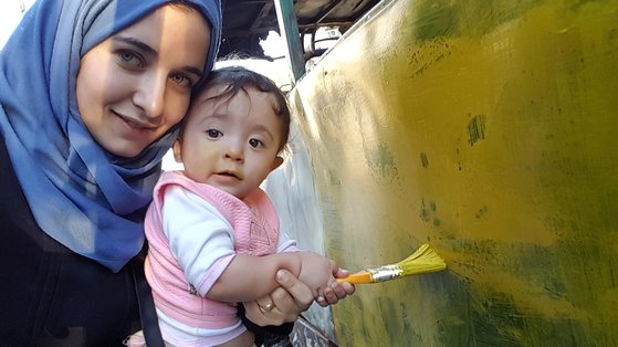 와드 알-카팁 감독과 한 살박이 사마. 내전 한복판에서 아이들은 붕괴된 버스를 놀이터삼아, 폭탄이 터졌을 때 해야 할 일들을 전래동화처럼 들으며 자란다. [사진 엣나인필름]