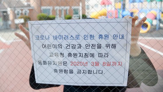 코로나19의 감염 확산을 미연에 방지하기 위해 전국의 어린이집과 유치원이 휴원한 지난달 27일 전북 전주시 덕진구 동화유치원에서 교사가 휴원 안내문을 붙이고 있다. 뉴시스