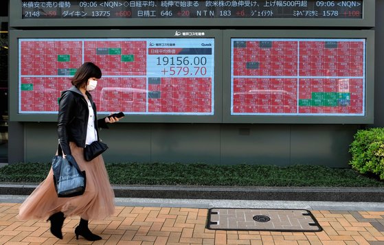 지난 7일 일본 도쿄 시내 증시 전광판 앞을 한 사람이 지나가고 있다. 연합뉴스