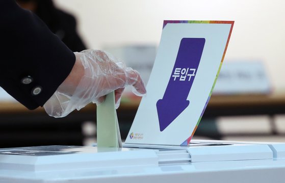 제21대 국회의원선거 투표일인 15일 서울 종로구 동성고등학교에 설치된 혜화동 제3투표소에서 비닐장갑을 낀 유권자가 투표함에 투표용지를 넣고 있다. [연합뉴스]