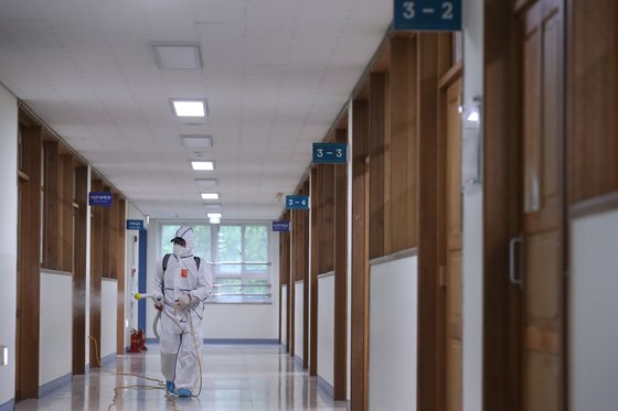 서울 이태원 클럽발 신종 코로나바이러스 감염증(코로나19) 집단 감염으로 학교들의 등교 재연기가 발표된 지난 11일 오후 서울 성동구 성수고등학교 3학년 교실 복도에서 방역업체 관계자가 소독을 하고 있다. 연합뉴스