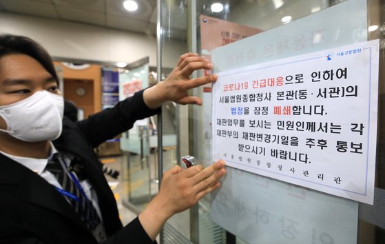 15일 오전 서울구치소 교도관이 신종 코로나바이러스 감염증(코로나19) 확진 판정을 받은 영향으로 서울 서초구 서울중앙지방법원 관계자가 법정 출입구에 폐쇄 안내문을 붙이고 있다. 뉴스1