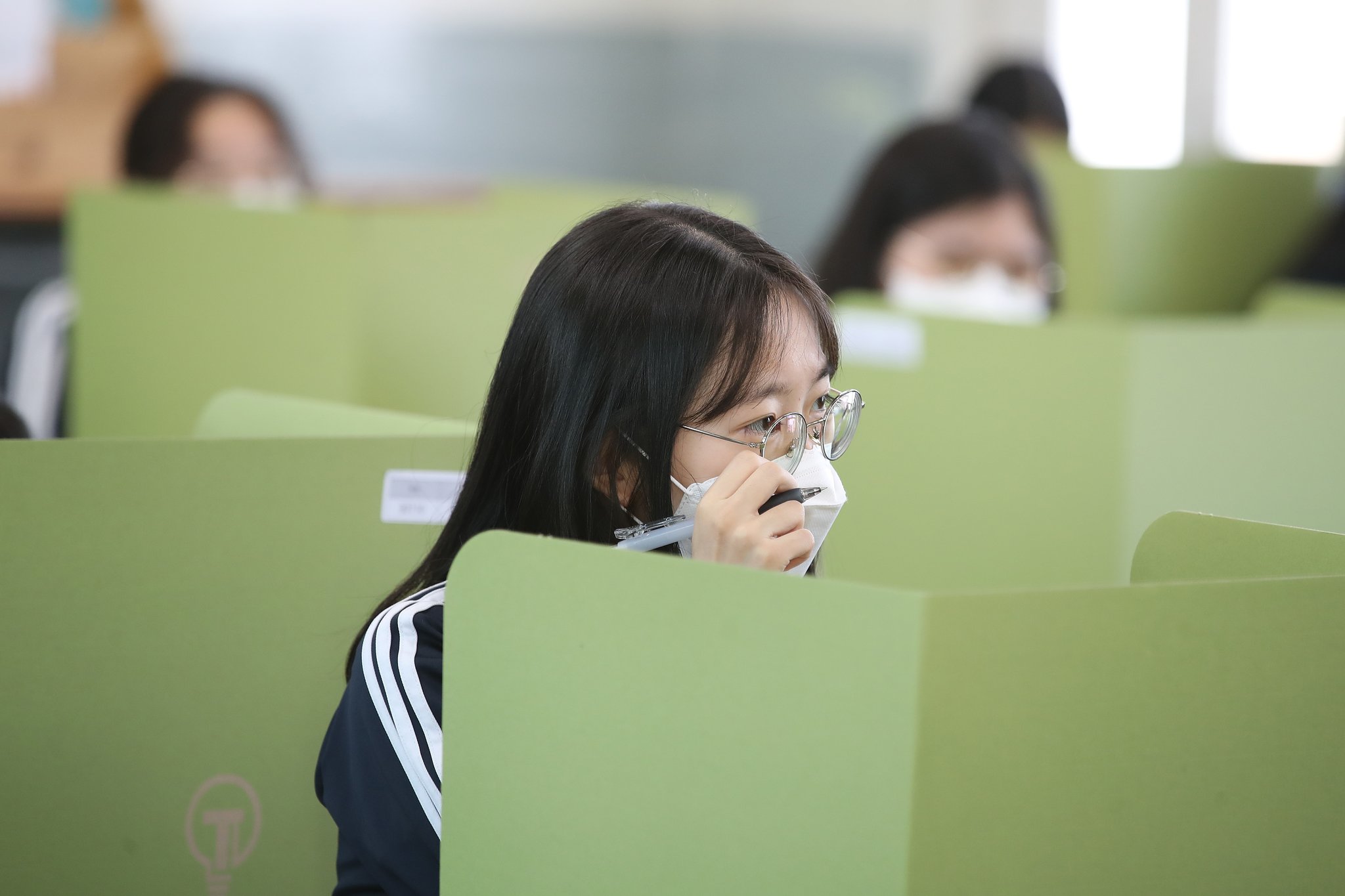 학생들 간 접촉을 줄이기 위한 갖가지 방법이 동원됐다. 교실은 물론 학생들이 점심을 먹는 식당 등에는 대화 중 비말로 인한 감염을 막기 위해 아크릴과 종이로 벽을 만들어졌다. 20일 대구 북구 경명여고 교실에서 마스크를 쓴 학생들이 동급생 사이에 처진 칸막이 너머로 수업을 듣고 있다. 뉴스1