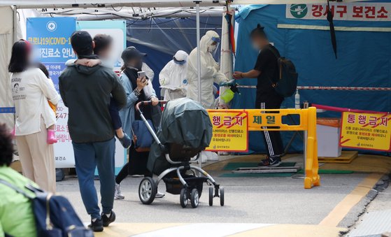 26일 서울 강서구 보건소 선별진료소를 찾은 학부모들이 아이와 함께 검사 순서를 기다리고 있다.뉴스1
