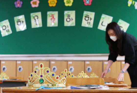 초등학교 1, 2학년 등교수업을 이틀 앞둔 25일 오후 경기도 수원시 매여울초등학교 1학년 교실에서 담임 교사가 학생들에게 전달할 왕관을 책상 위에 놓고 있다. 연합뉴스