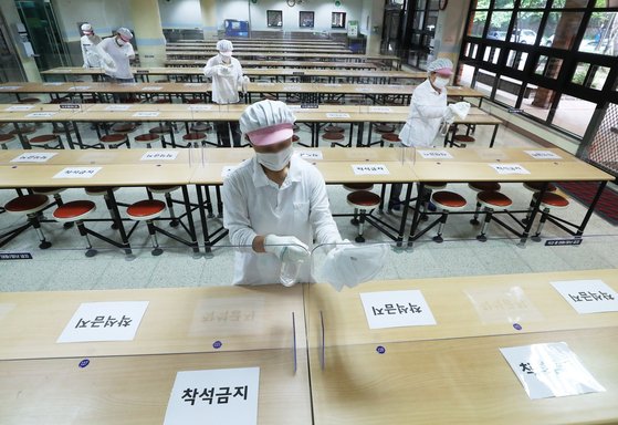 초등학교 1, 2학년 등교수업을 이틀 앞둔 25일 오후 경기도 수원시 매여울초등학교 급식실에서 관계자들이 테이블과 칸막이 등을 소독하고 있다. 연합뉴스