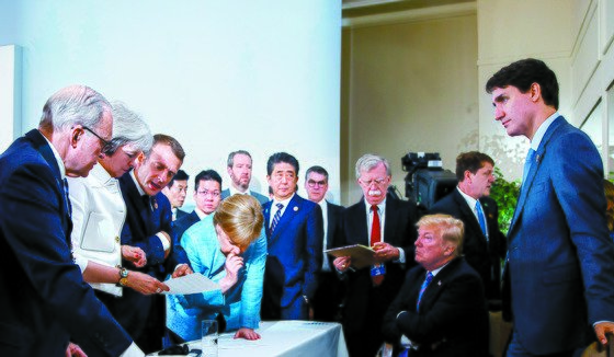 2018년 6월 캐나다 샤를부아에서 열린 주요 7개국(G7) 정상회의에서 참석자들이 통상문제가 포함된 공동성명 문안을 논의하고 있다. 왼쪽부터 장클로드 융커 유럽위원회 위원장, 데레사 메이 영국 총리, 에마뉘엘 마크롱 프랑스 대통령, 앙겔라 메르켈 독일 총리, 아베 신조 일본 총리, 존 볼튼 미국 국가안보 보좌관, 도널드 트럼프 미 대통령, 주세페 콘테 이탈리아 총리, 쥐스탱 트뤼도 캐나다 총리. [로이터=연합뉴스]