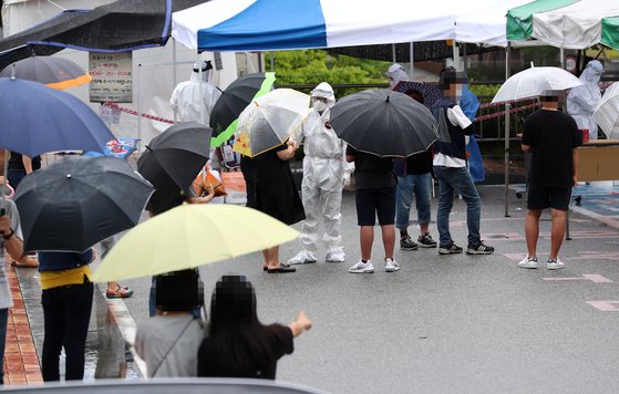 30일 오전 대전시 동구 가오동 동구보건소에 마련된 신종 코로나바이러스 감염증(코로나19) 선별진료소에서 확진자와 접촉한 초등학생들이 가족과 함께 검사 순서를 기다리고 있다. 연합뉴스