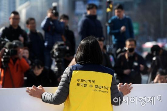 세월호 천막이 철거되고 있는 가운데 참사 유족이 진상규명 및 책임자 처벌을 촉구하는 내용을 담은 대형 피켓을 들고 있다. 조끼에 적힌 '부모이기에 포기할 수 없습니다' 문구가 눈에 띈다. /문호남 기자 munonam@