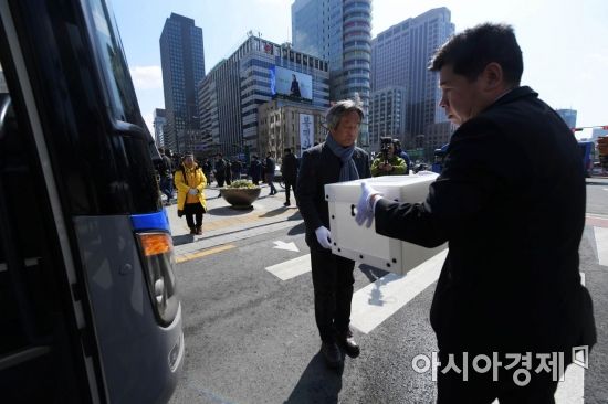 세월호 참사 희생자 및 미수습자 분향소에서 열린 이운식에서 관계자들이 희생자 영정이 담긴 상자를 버스에 싣고 있다. 뒤편 한 유족이 두 손을 모은 채 버스를 바라보고 있다. /문호남 기자 munonam@