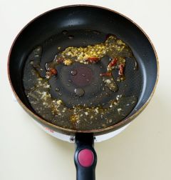 3. 팬에 고추기름과 식용유를 두르고 다진 마늘과 마른 고추를 넣어 타지 않게 1분 정도 볶다가 물 1/2컵을 넣는다.