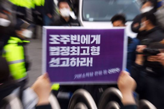 지난 25일 인터넷 메신저 텔레그램에서 미성년자를 포함한 여성들의 성 착취물을 제작 및 유포한 혐의를 받는 '박사방' 운영자 조주빈이 탄 차량이 서울 종로경찰서를 나와 검찰 유치장으로 향하자 시민들이 조주빈의 강력처벌을 촉구하며 피켓 시위를 하고 있다. [이미지출처=연합뉴스]