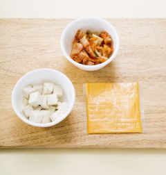 2. 배추김치는 작게 썰어 팬에 식용유를 두른 뒤 살짝 볶는다.두부는 작은 주사위 모양으로 썰고 슬라이스 치즈는 굵게 다진다.