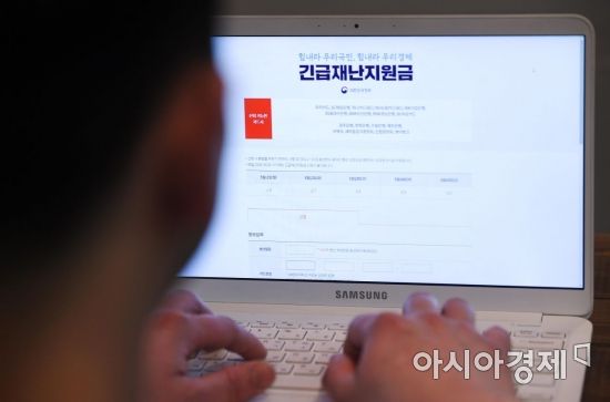 정부의 긴급재난지원금 신용·체크카드 충전 신청이 11일 오전 7시 9개 카드사 홈페이지를 통해 시작됐다. 공적 마스크 5부제와 마찬가지로 신청에는 요일제가 적용되고 16일부터는 언제든 신청할 수 있게 바뀐다. 지원금은 1인 가구 40만원, 2인 가구 60만원, 3인 가구 80만원, 4인 이상 가구 100만원이다. 사진은 이날 서울 종로구의 한 시민이 지원금을 신청하는 모습./김현민 기자 kimhyun81@