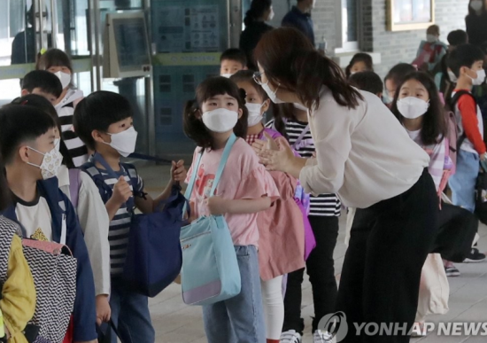 고등학교 2학년과 중학교 3학년, 초등학교 1∼2학년, 유치원생들이 등교 수업을 시작한 27일 오전 전북 전주시 완산구 효천초등학교에서 1학년들이 교실로 들어가기 전에 선생님과 이야기하고 있다. [이미지출처=연합뉴스]