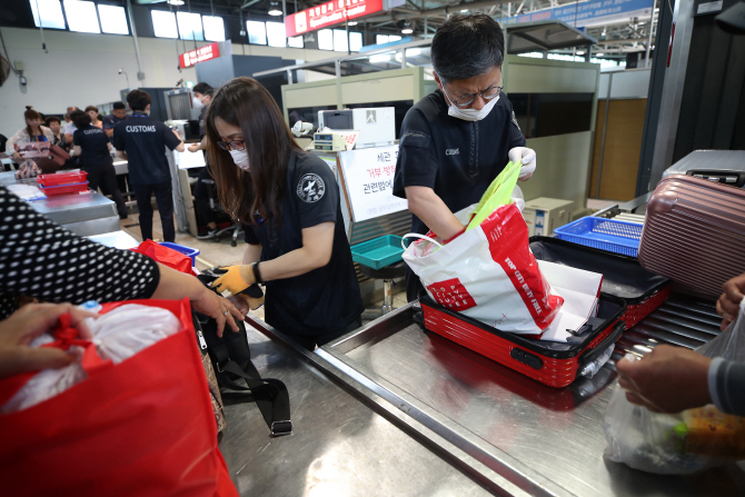 지난달 18일 인천항 제2국제여객터미널에서 세관 직원들이 입국 관광객 대상으로 아프리카돼지열병(ASF) 검역을 하고 있다. 연합뉴스 제공