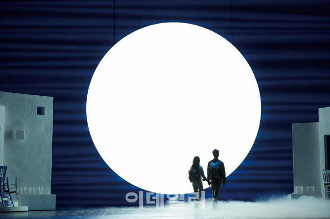 맘마미아의 한 장면. 극중 소피(이수빈)와 그의 남자 친구인 스카이(신현묵)가 넘버(삽입곡) ‘I have a dream’을 부르고 있다. 무대 위 달은 200여 개의 형광등으로 구현한 것이다(사진=신시컴퍼니)