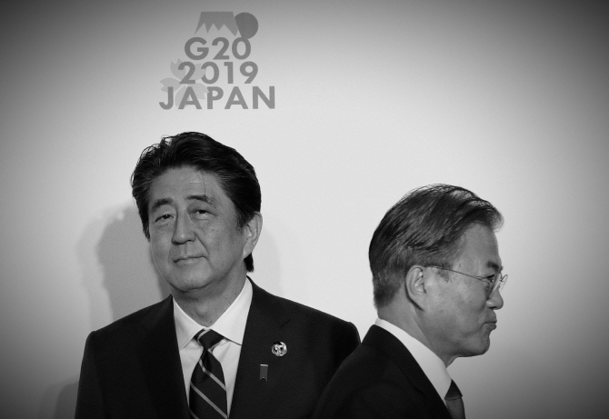 6월 일본 오사카에서 열린 주요20개국 정상회담에 참석한 문재인 대통령(오른쪽)이 아베 신조 일본 총리(왼쪽)와 인사 후 스쳐지나고 있다.[AFPBB제공]