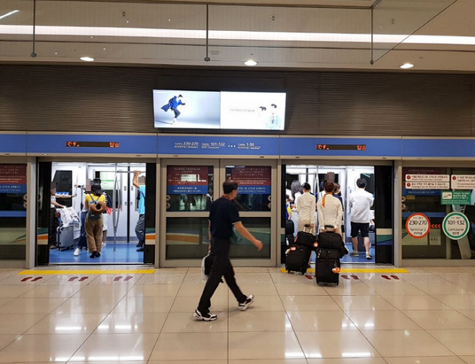 여행객과 승무원이 인천공항에서 셔틀트레인에 탑승하고 있다.