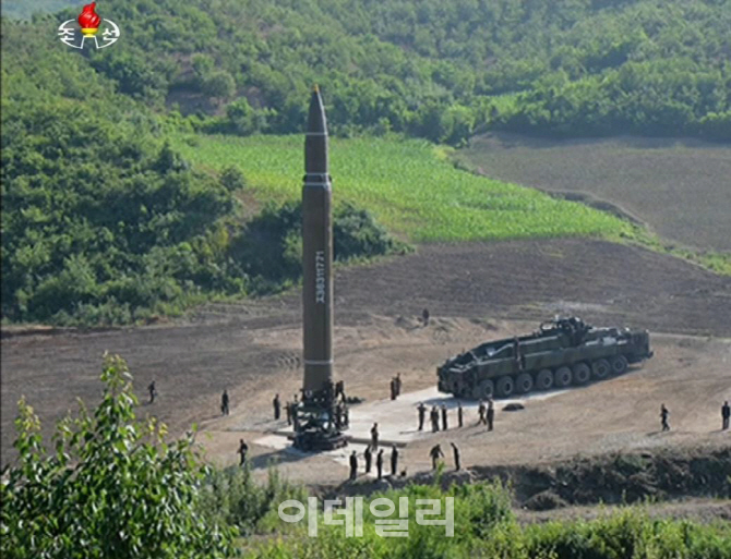 북한 조선중앙TV가 공개한 화성-14 발사 준비 모습이다. 이동식 발사 차량에서 탄도미사일을 내려 지상 거치형 고정식 발사대에 세우고 있다. [사진=연합뉴스]