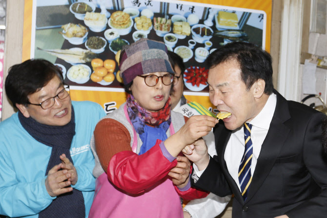 손학규 바른미래당 대표가 21일 충북 청주 육거리시장에서 자체 제작한 여성정책홍보 카트로 시민들에게 차를 나눠주며 캠페인을 한 뒤 시장에서 한 상인이 건넨 전을 먹고 있다. (사진=뉴시스)