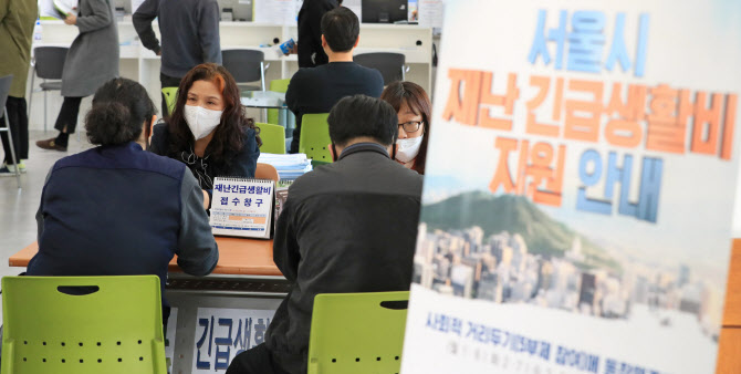 30일 오후 서울 송파구 마천2동 주민센터에서 직원들이 주민에게 긴급생활비 신청 여부를 안내하고 있다. 연합뉴스 제공