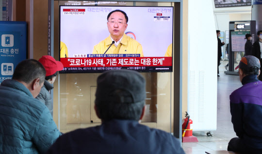 30일 오후 서울역에서 시민들이 비상경제회의 결과 관계부처 합동브리핑을 보고 있다.(사진=연합뉴스)