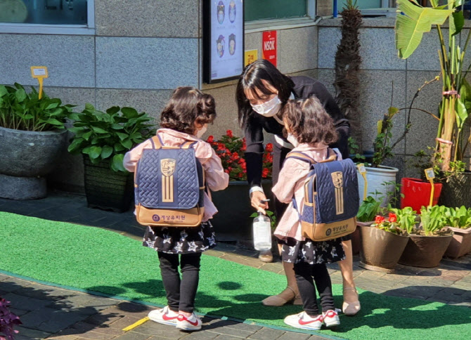 신종 코로나바이러스 감염증(코로나19) 사태로 미뤄졌던 유치원과 초등학교 1∼2학년, 중학교 3학년, 고등학교 2학년생의 등교 개학일인 27일 오전, 서울 양천구 신정3동 계상유치원 선생님이 등원 전 마스크를 착용한 원생들의 손을 소독하고 있다. (사진=연합뉴스)
