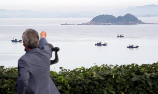 북한이 금강산 관광지구와 개성공단, 비무장지대(DMZ) 내 감시초소(GP)에 군부대를 재주둔시키겠다고 밝힌 17일 오전 인천시 옹진군 대연평도 망향전망대에서 한 시민이 북측 해역을 바라보고 있다(사진=연합뉴스).
