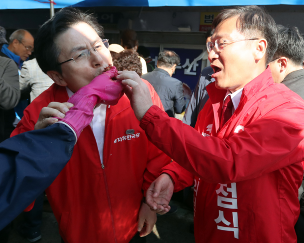 한 상인이 22일 오후 경남 통영시 통영중앙시장에서 자유한국당 황교안(왼쪽) 대표에게 멍게를 건네고 있다. 오른쪽은 같은 당 4·3 보궐선거 통영·고성 정점식 후보. /연합뉴스