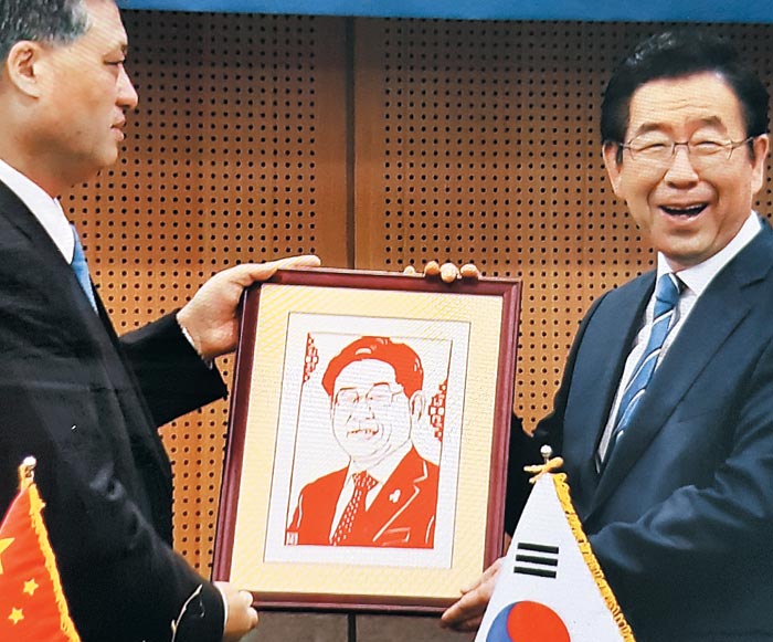 5일 오전 서울시청에서 박원순(오른쪽) 서울시장이 중국 광둥성 경제사절단이 착오로 선물한 이재명 경기지사의 초상화를 받아들고 있다. /연합뉴스