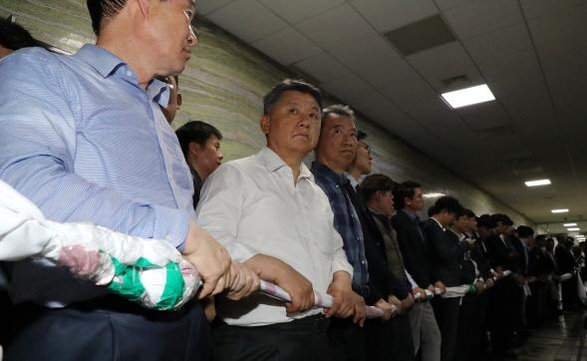 자유한국당 의원과 보좌진들이 25일 밤 여야4당의 법안 제출을 막기 위해 국회 의안과 앞에서 인간띠를 두르고 있다./연합뉴스