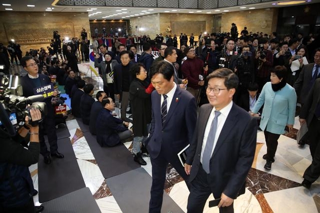 23일 오후 국회 본회의장 앞에서 자유한국당 의원들이 연좌 농성중인 가운데 더불어민주당 의원들이 본회의장으로 들어서고 있다. /연합뉴스