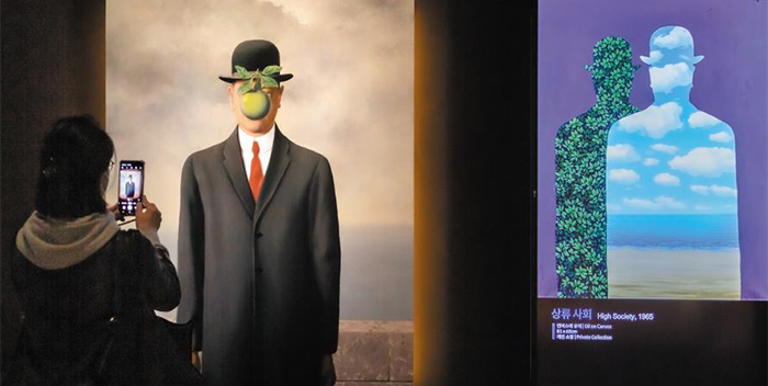 한 관람객이 ‘마그리트 특별전’에 마련된 르네 마그리트의 회화를 재구성한 작품 앞에서 사진을 찍고 있다. 미디어아트·증강현실 등 첨단 기술을 동원해 작가의 상상력을 구현한 체험형 전시다. /지엔씨미디어