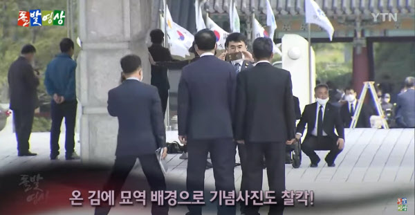 김남국 당선자가 5.18 민주묘지를 배경으로 사진을 찍어주고 있는 모습. /YTN