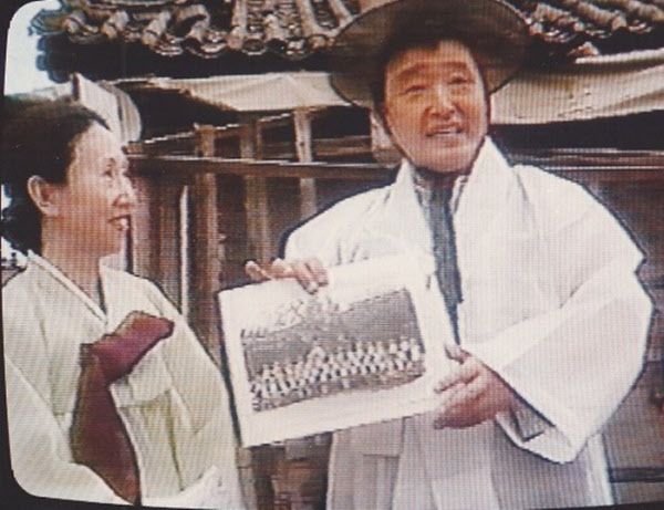 어릴 적 살던 서울 창신동 '큰대문집' 앞에서 유치원 졸업 사진을 들고 있는 백남준과 이경희. 장 폴 파르지에(Jean Paul Fargier) 촬영. 1990.