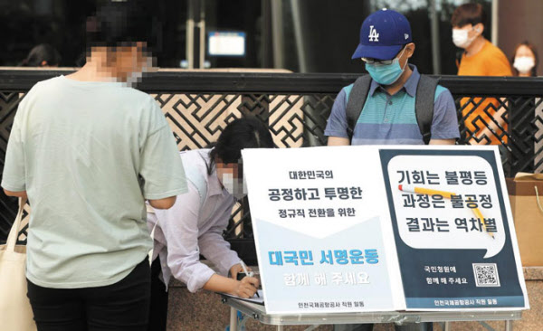 26일 오후 서울 광화문역 앞에서 인천국제공항공사 정규직 직원이 ‘공정하고 투명한 정규직 전환을 위한 대국민 서명 운동’이라고 쓰인 팻말을 걸고 시민들의 지지 서명을 받고 있다. 인천공항공사 직원 50명은 서울의 지하철역 9곳에서 서명 운동을 벌였다. /장련성 기자