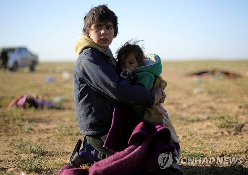 이달 1일 IS 진영에서 빠져나온 후 아기를 안은 채 앉아 있는 소년    [로이터=연합뉴스]