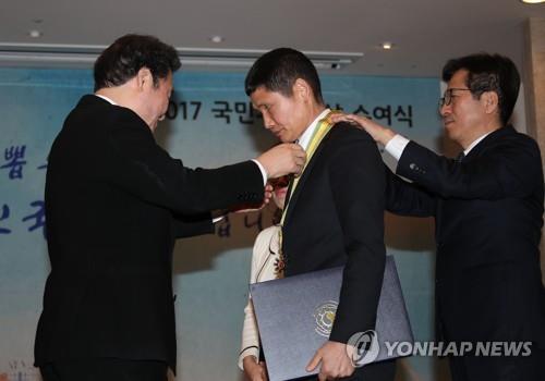 국민훈장 동백장 받는 '파란 바지의 의인' 김동수씨(서울=연합뉴스) 김승두 기자 = 이낙연 국무총리가 31일 오후 서울 세종로 정부서울청사에서 열린 국민추천포상 수여식에서 세월호 사고현장에서 소방호스로 수십 명의 목숨을 살린 '파란 바지의 의인' 김동수(54)씨에게 국민훈장 동백장을 주고 있다. 2018.1.31