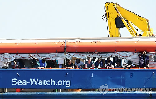 네덜란드 구조선 '시워치3'에 승선한 난민들(로마 로이터=연합뉴스) 지중해에서 난민을 구조한 후 2주간 공해상을 떠돌다 26일(현지시간) 이탈리아령 람페두사섬 인근을 항해하는 네덜란드 국적 구조선 '시워치(Sea-Watch)3'에서 난민들이 손을 흔들고 있다. 이 선박은 사흘 뒤 람페두사에 입항했다.