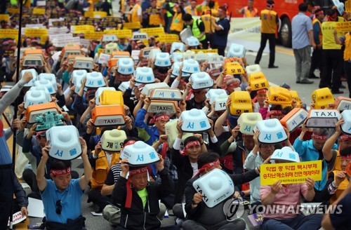 개인택시기사, 전국순례투쟁(세종=연합뉴스) 진성철 기자 = 19일 세종시 정부세종청사 국토교통부 앞에서 열린 '타다 아웃, 택시규제 혁신! 전국순례투쟁'에 참가한 서울개인택시운송사업조합원들이 '택시 방범등'을 흔들며 '타다처벌, 택시규제혁신'을 외치고 있다. 2019.6.19