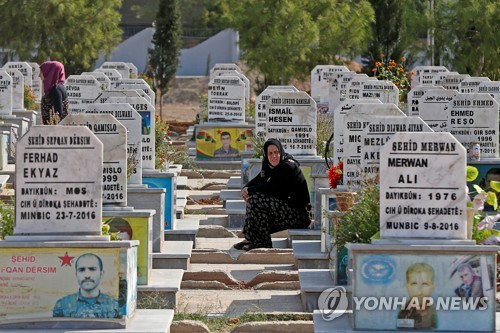 22일 시리아 북부 까미슐리에 있는 묘지에서 전사자를 애도하는 쿠르드인   [로이터=연합뉴스]
