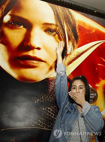 군부 쿠데타가 일어난 해인 2104년 당시 태국의 한 반군부 운동가가 영화 헝거게임 포스터 앞에서 저항의 상징 '세 손가락' 인사를 하고 있다. 2014.11.20.
[EPA=연합뉴스]