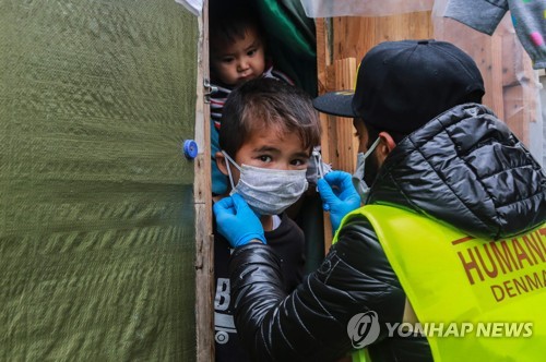 그리스 레스보스섬 내 난민캠프에서 생활하는 어린이에 면 마스크를 씌워주는 비정부 지원단체 직원. 2020.3.28. [AFP=연합뉴스]