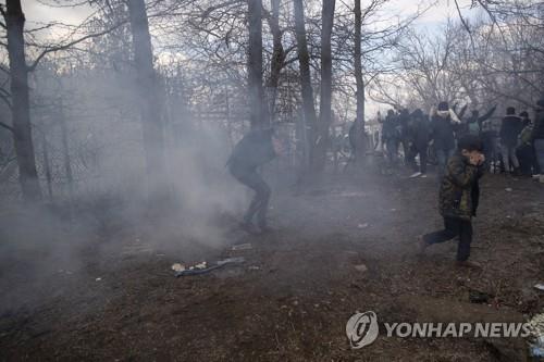 그리스 경찰이 발사한 최루탄에 돌아서는 난민들 [EPA=연합뉴스]