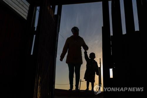 한 어머니가 21일 케이프타운에서 아침 영양팩을 받으러 아이를 데려오고 있다.[EPA=연합뉴스]