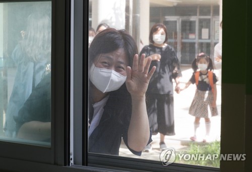 아들! 잘하고 와(세종=연합뉴스) 김주형 기자 = 신종 코로나바이러스 감염증(코로나19) 사태로 미뤄졌던 유치원과 초등학교 1∼2학년, 중학교 3학년, 고등학교 2학년의 등교 개학일인 27일 오전 세종시 연양초등학교에서 한 학부모가 교실 밖에서 자녀에게 손 흔들고 있다. 2020.5.27 kjhpress@yna.co.kr