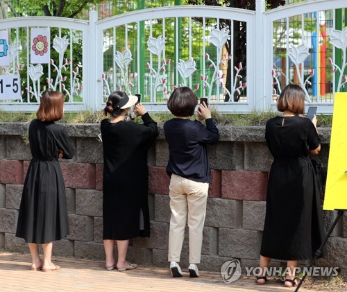 '떨어지지 않는 발길'(청주=연합뉴스) 이승민 기자 = 고등학교 2학년과 중학교 3학년, 초등학교 1∼2학년, 유치원생들의 등교 수업이 시작된 27일 오전 청주시 청원구 중앙초등학교 담장 너머로 학부모들이 학생을 바라보고 있다. 2020.5.27 logos@yna.co.kr